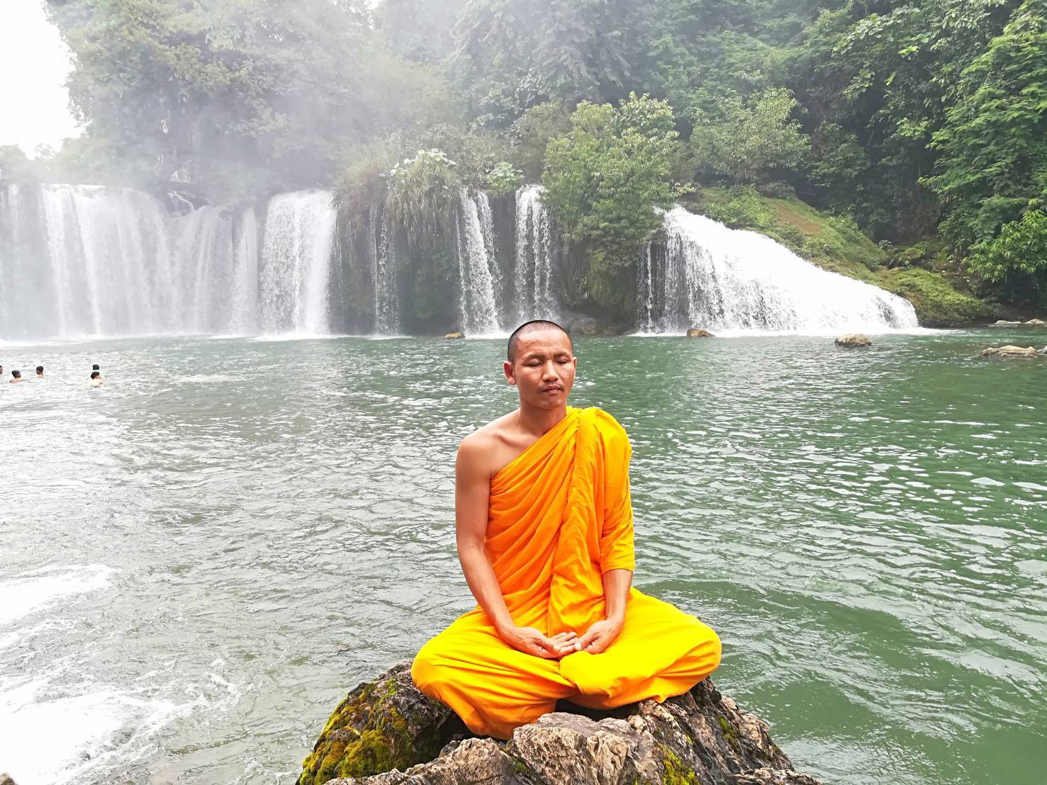 พระสงฆ์นั่งสมาธิที่น้ำตก
