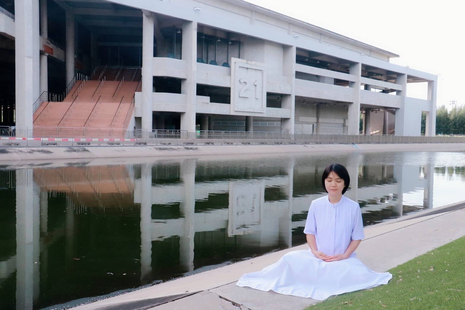 หญิงสาวนั่งสมาธิริมสระน้ำ