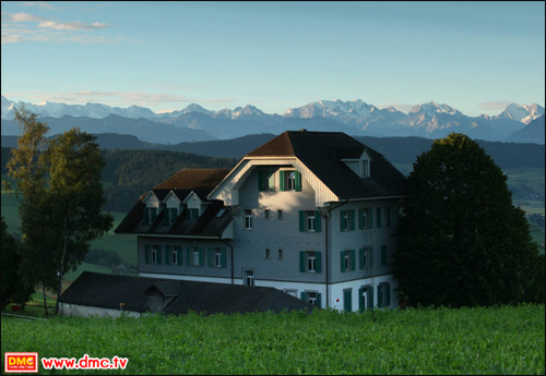 “วัดพระธรรมกายสวิตเซอร์แลนด์” ในช่วงฤดูร้อน ตัวอาคารรูปทรงสง่า  ตั้งอยู่บนทิวทัศน์ที่สวยงามโอบล้อมด้วยเทือกเขาแอลป์แบบพาโนราม่า
